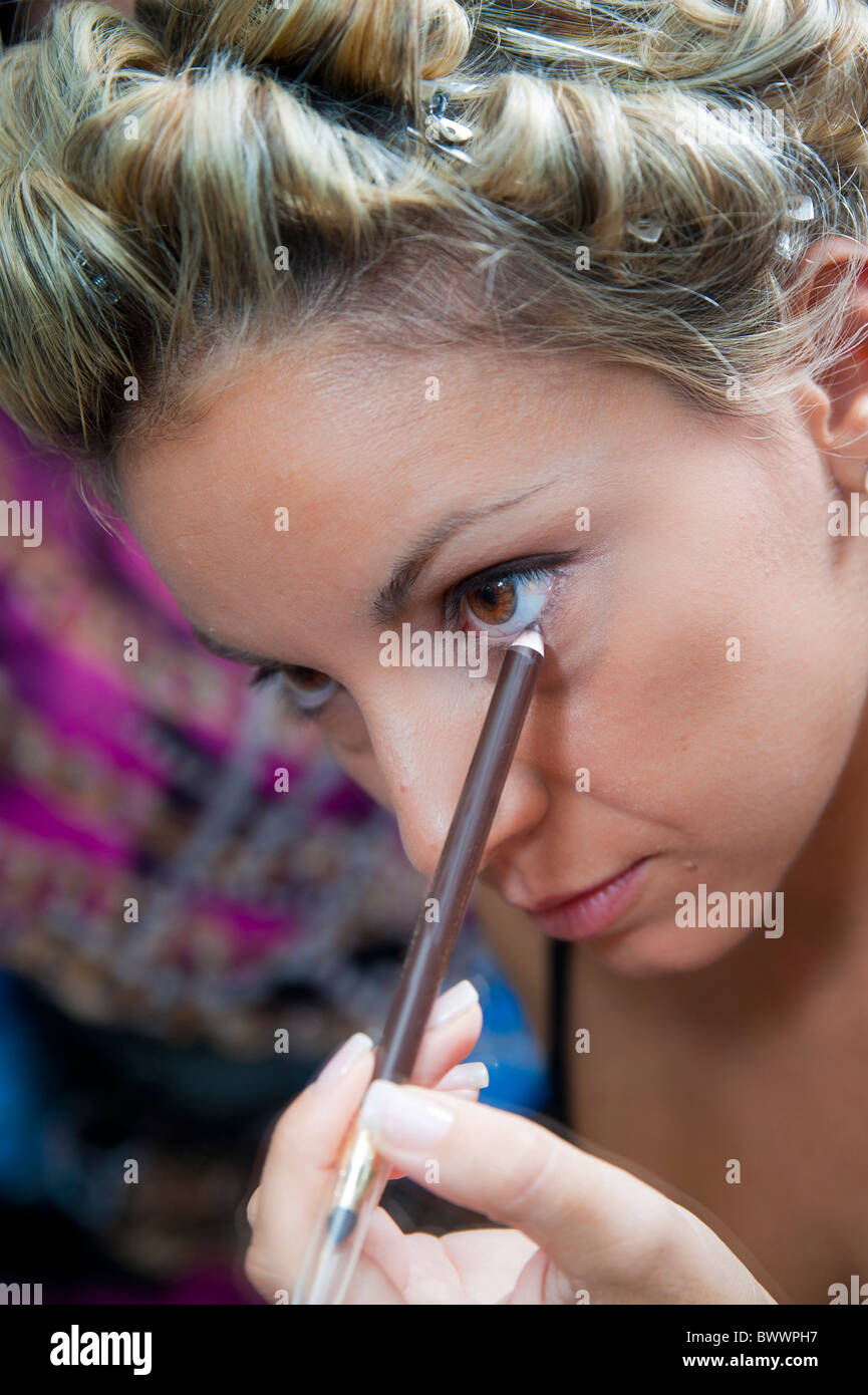Woman self applying make up with an eyeliner pencil Stock Photo