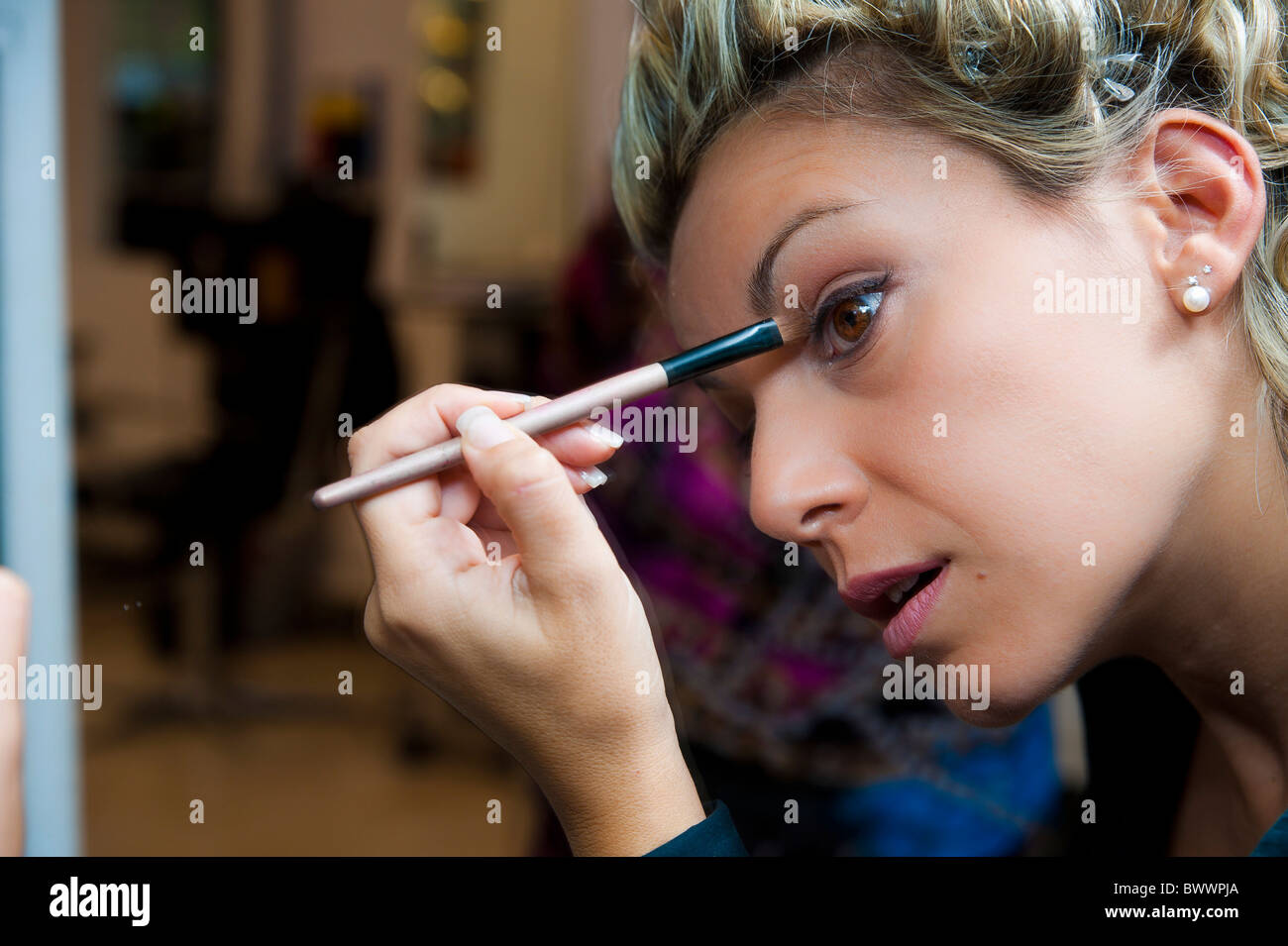 Woman self applying make up with a brush Stock Photo
