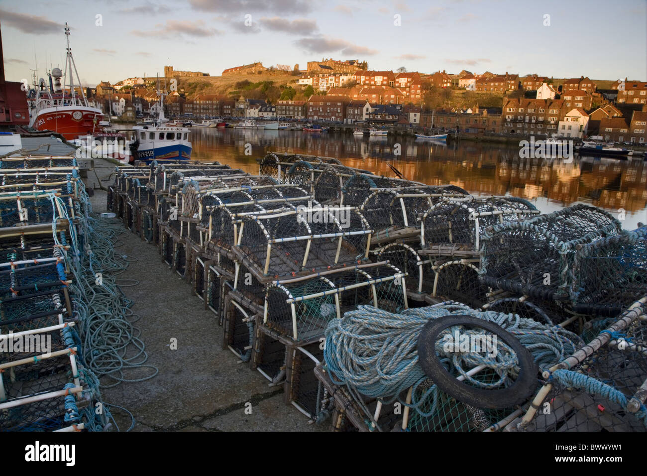 Lobster pots on quayside of coastal town, distant view of Whitby Abbey