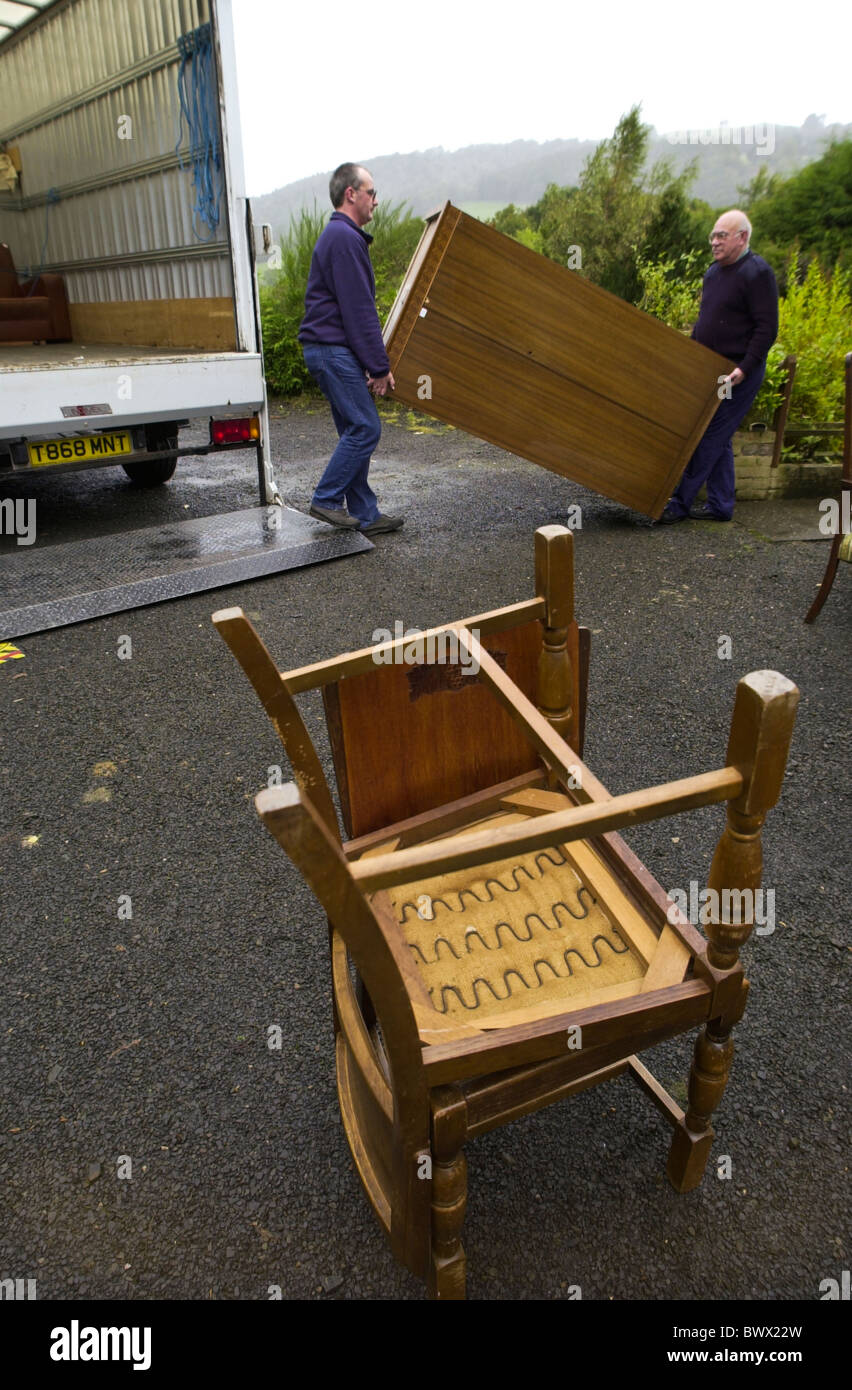 Two men loading furniture into removal van from a rural house for a