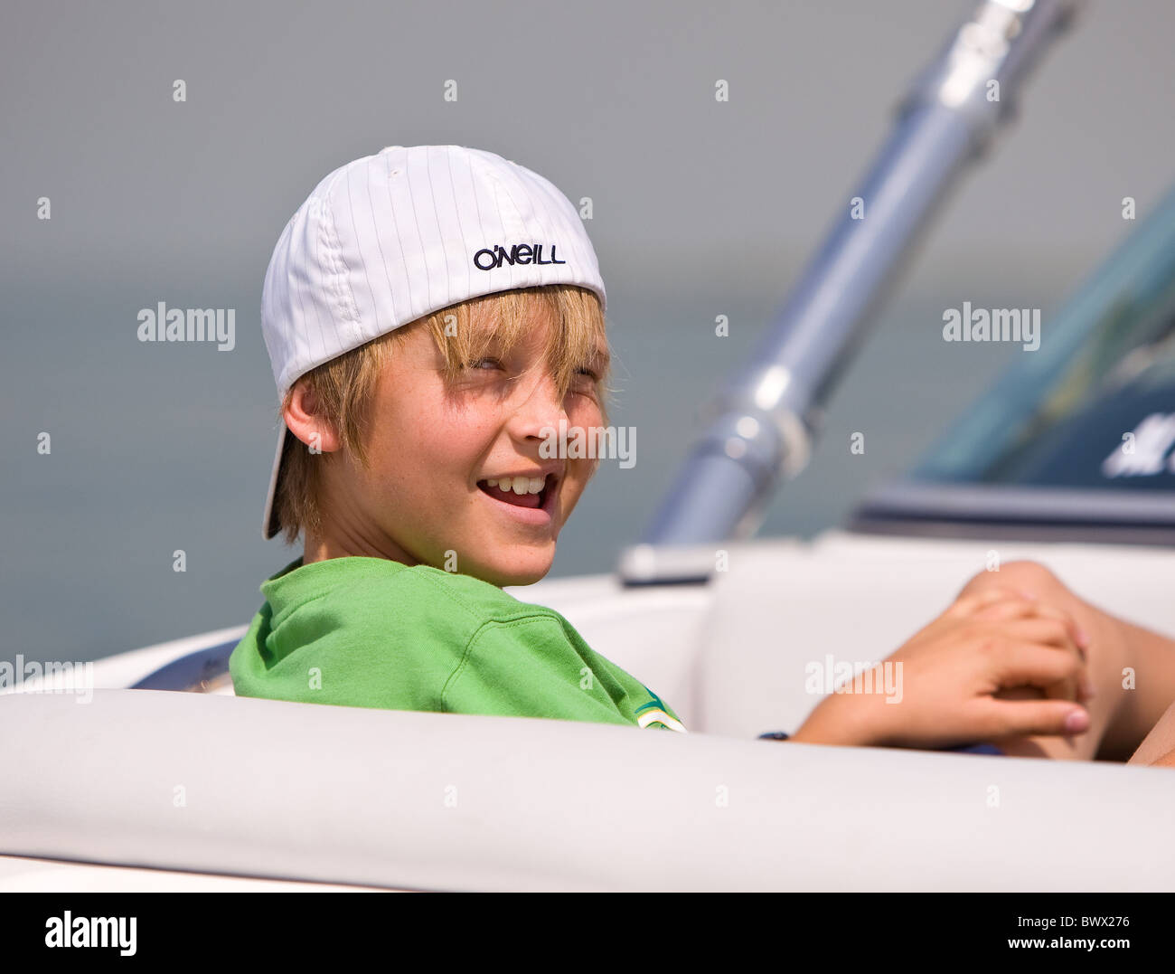 Cheeky young boy with hat reversed sat in a speed boat Stock Photo