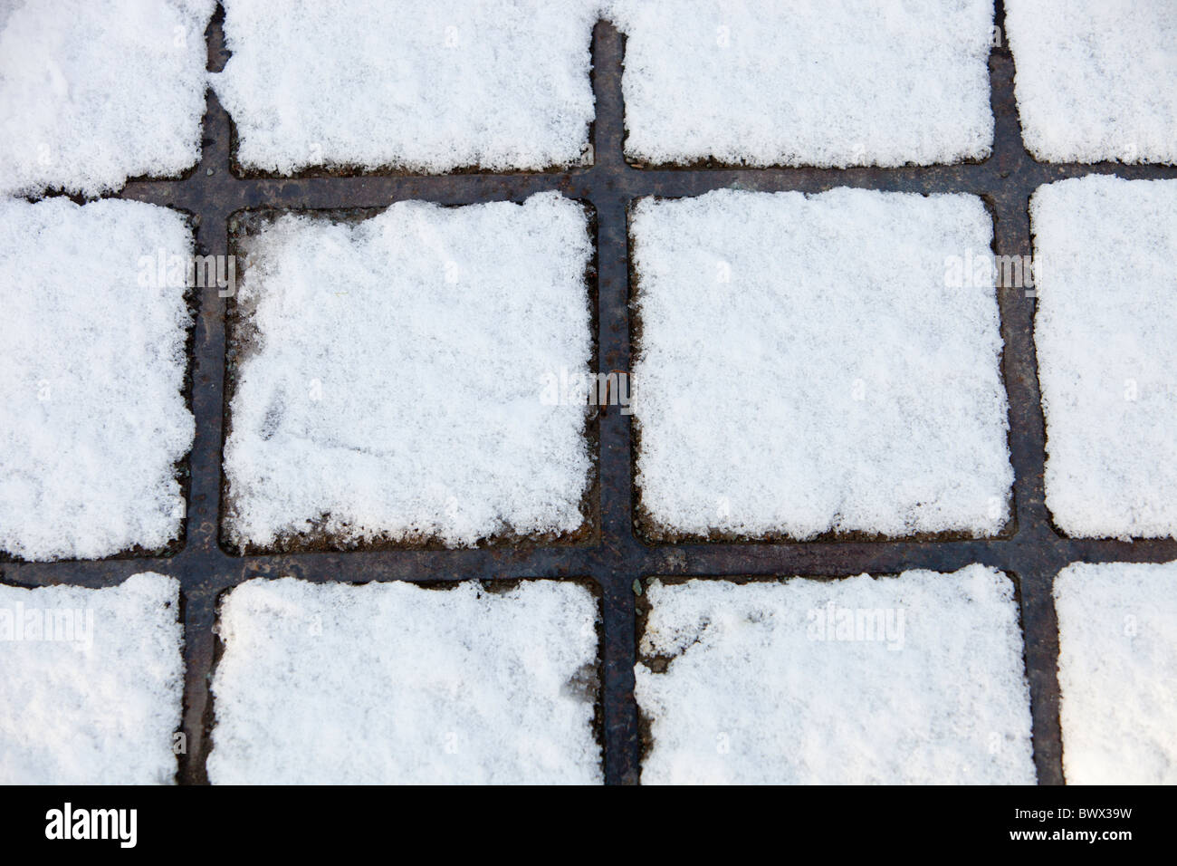 A pattern formed by snow melt on a man hole cover. Stock Photo