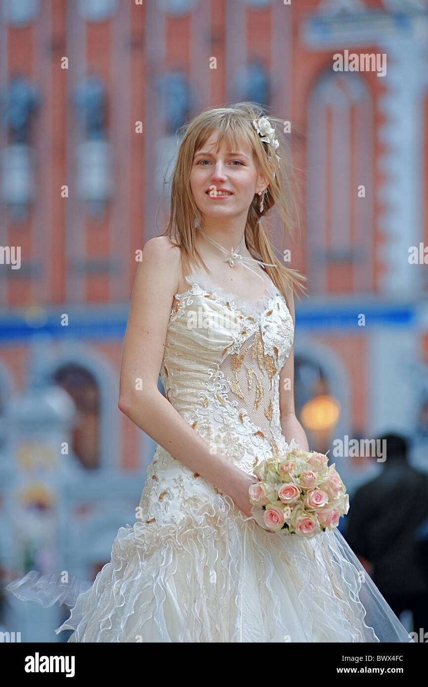 Bride in light dress with cream-colour rose bouquet in her hands and white flowers in her hair. Stock Photo