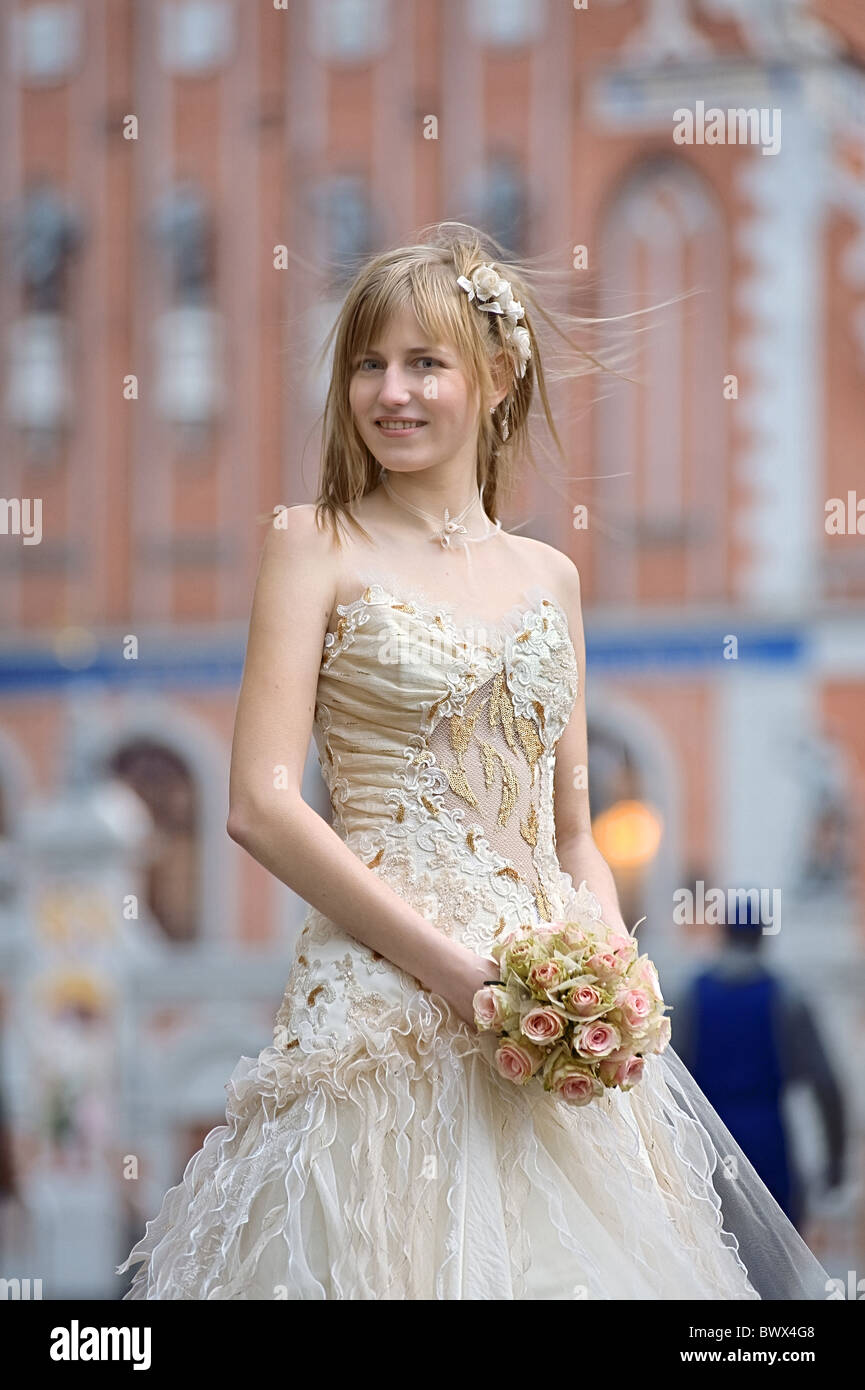 Bride in light dress with cream-colour rose bouquet in her hands and white flowers in her hair. Stock Photo