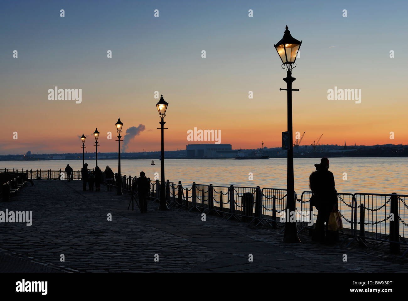 People enjoying the sunset over the River Mersey on the Liverpool Promenade at Albert Dock. Stock Photo