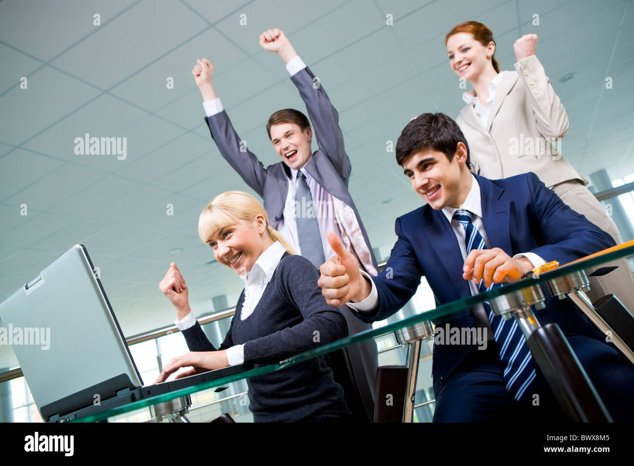 Group of co-workers looking at laptop monitor with expression of gladness Stock Photo