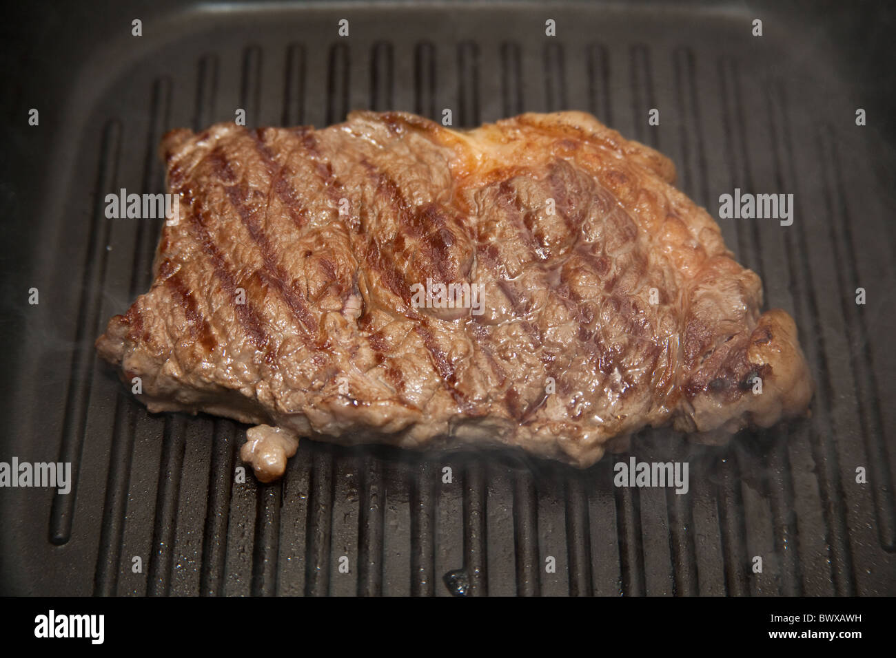 Rump steak being cooked in a griddle pan. Stock Photo