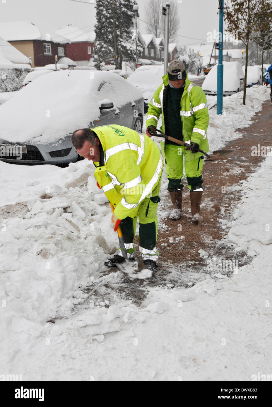 Council workers clearing and gritting the pavement. Stock Photo