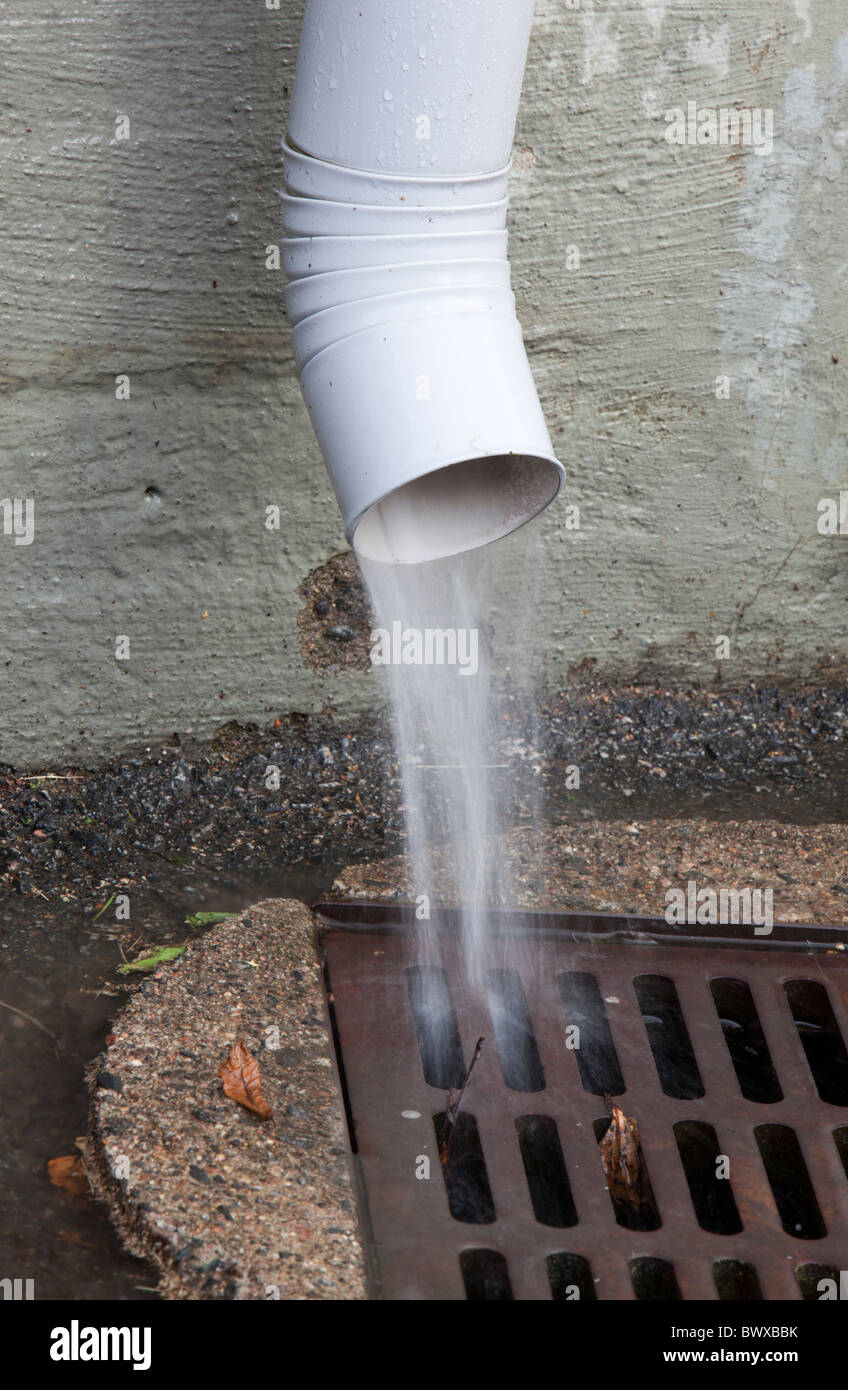 Downspout spewing water to drain Stock Photo