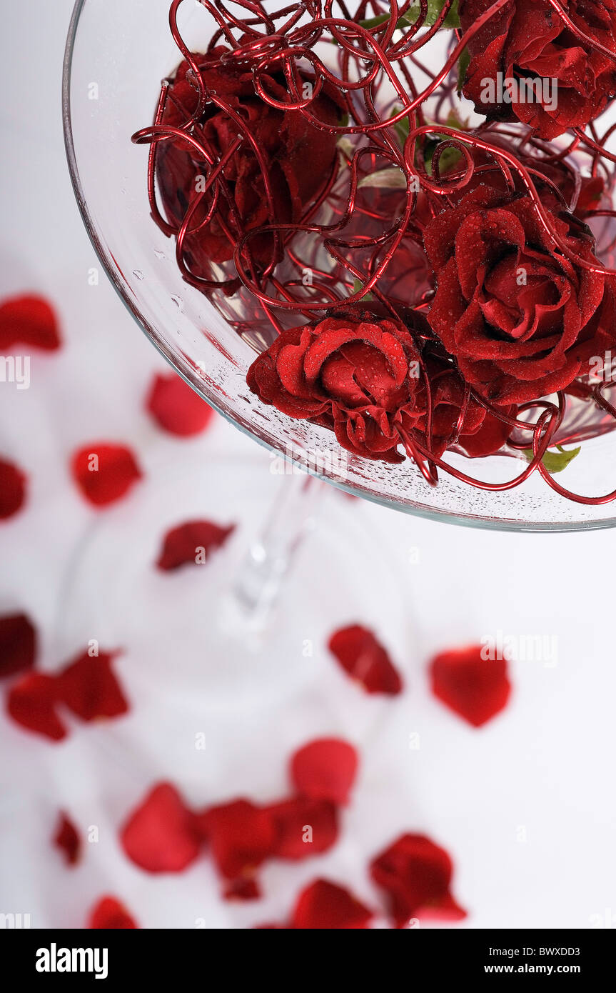 Modern floral table center using red rose petals and metallic red wire in a large tall stemmed glass Stock Photo