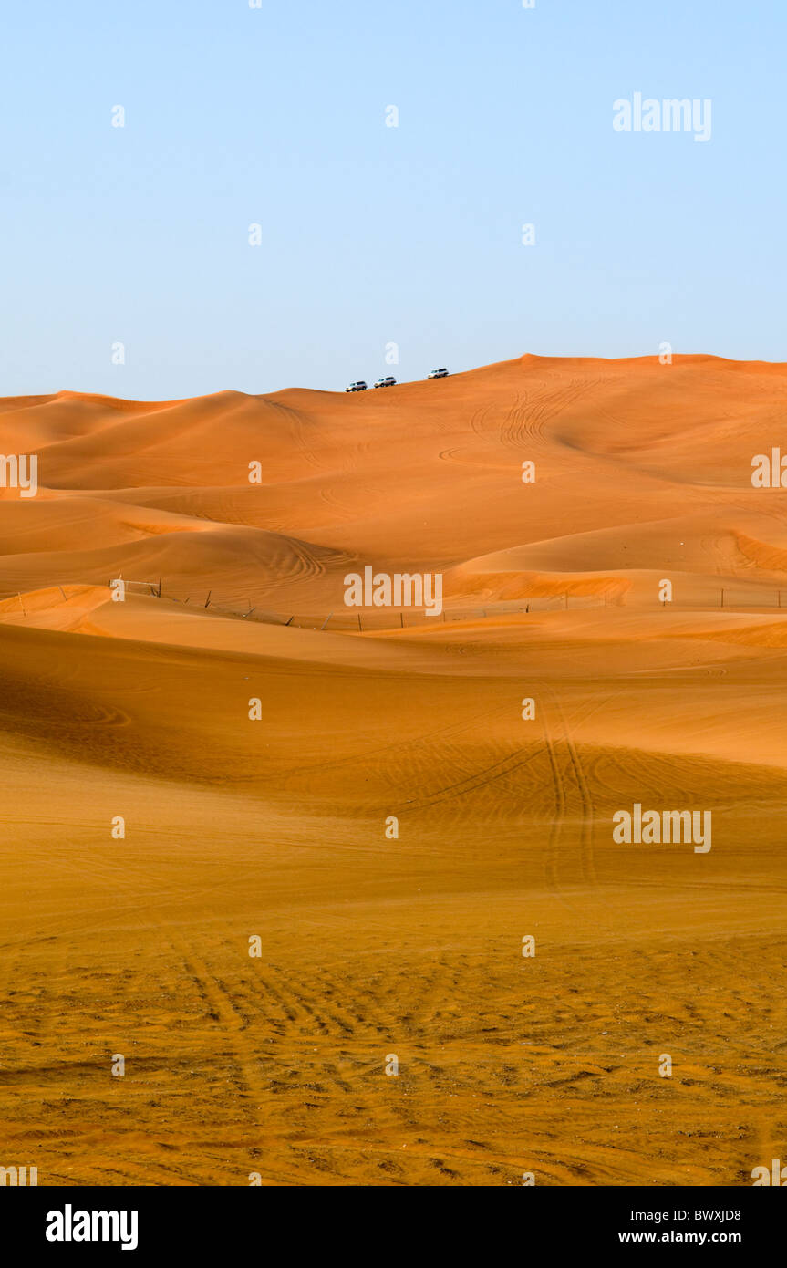 Three four wheel drive vehicles at the top of a sand dune in the desert ...