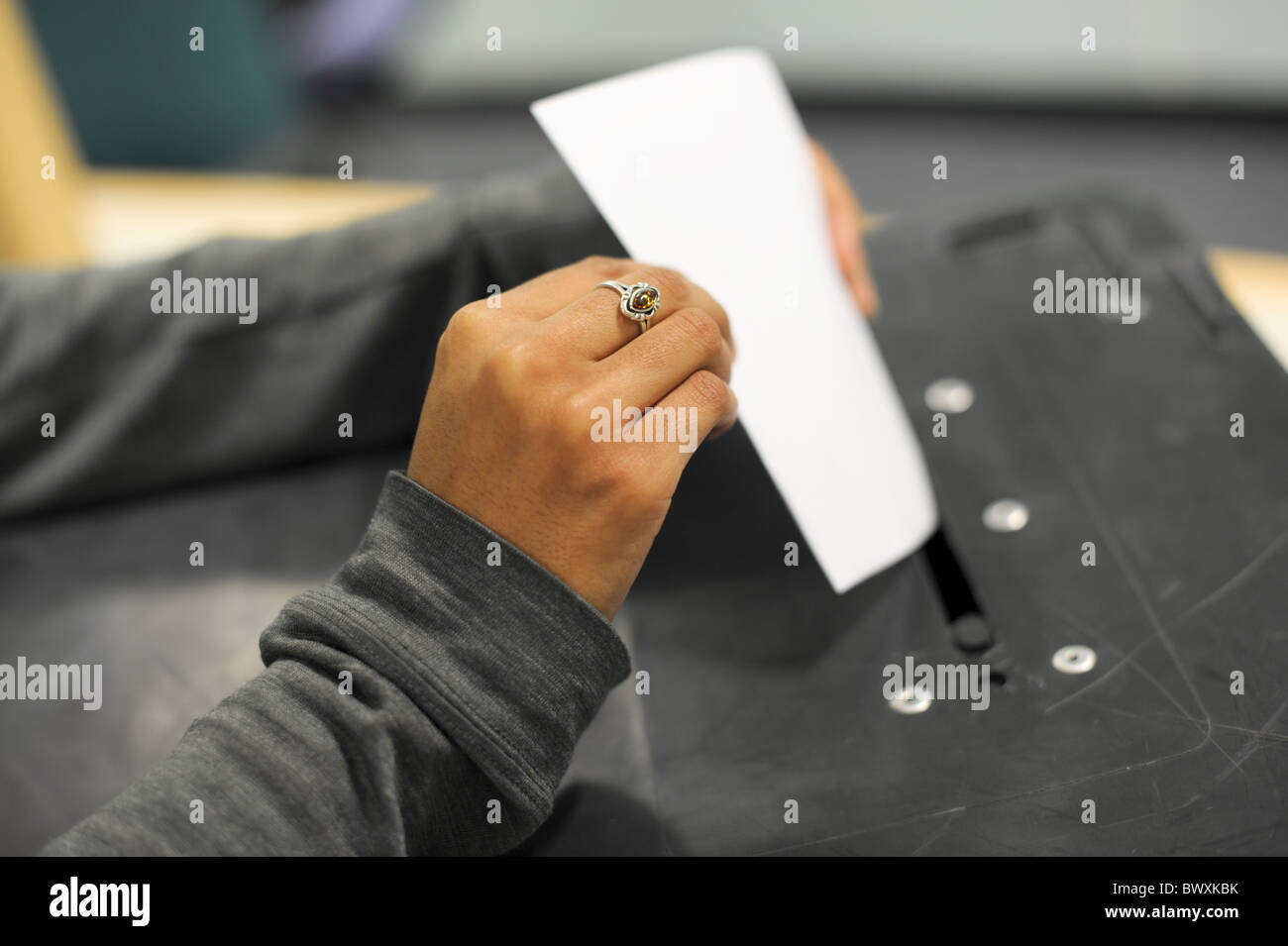 Young Asian woman's hand holding a ballot paper and putting into a ballot box at an election Stock Photo