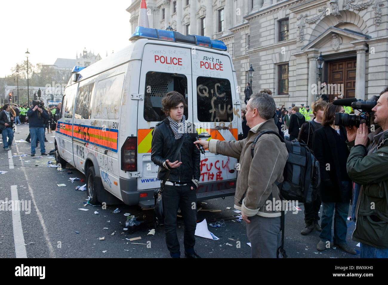 A student being interviewed by the media in front of a wrecked Metropolitan police vehicle. Stock Photo