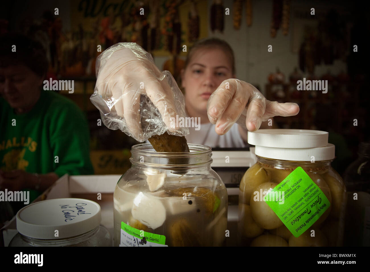 woman takes pickle from jar at deli Stock Photo