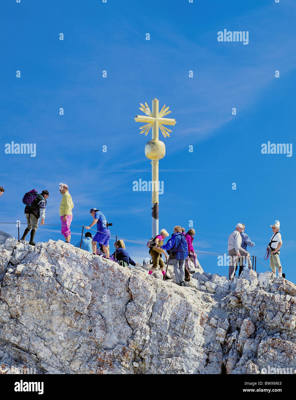 walking hiking group Zugspitze summit peak rocky summit cross golden Germany Europe Bavaria mountain walki Stock Photo