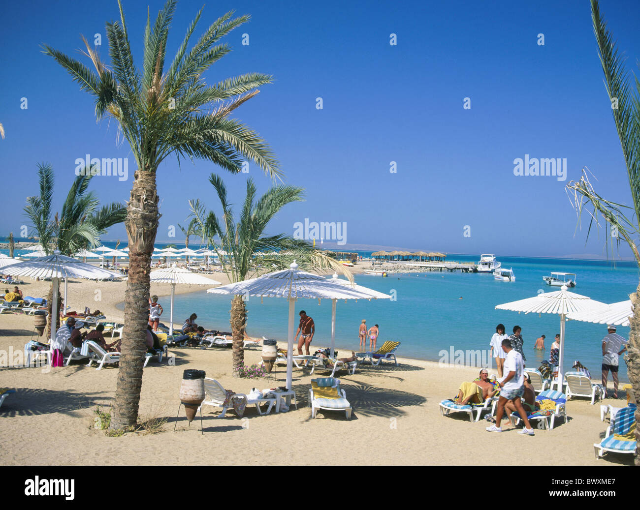 Egypt North Africa beach hotel Hilton Hurghada people palms sunshades beach holidays Stock Photo
