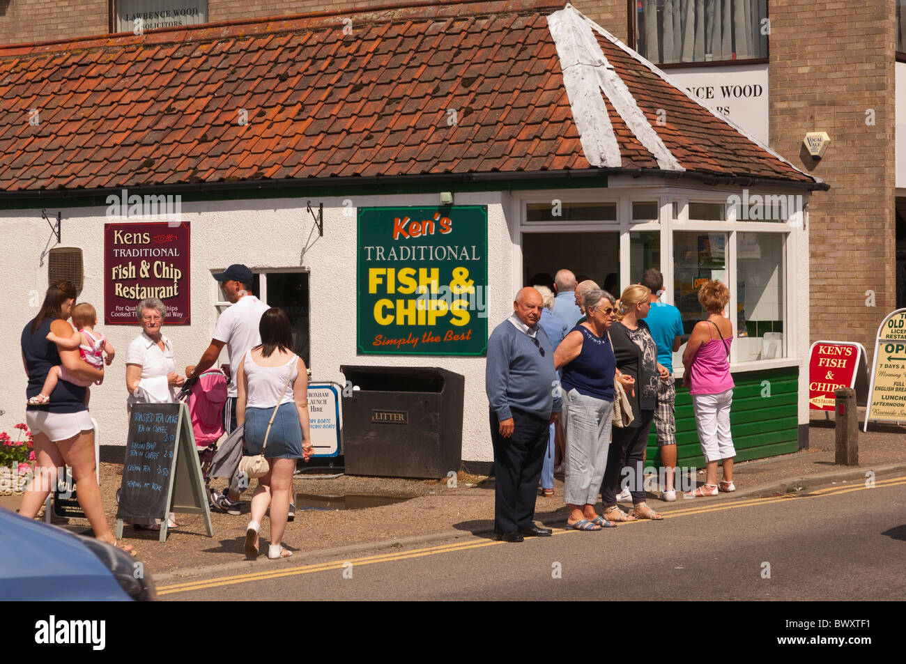 People outside Kens traditional fish and chips chip shop restaurant in Wroxham , Norfolk , England , Great Britain , Uk Stock Photo