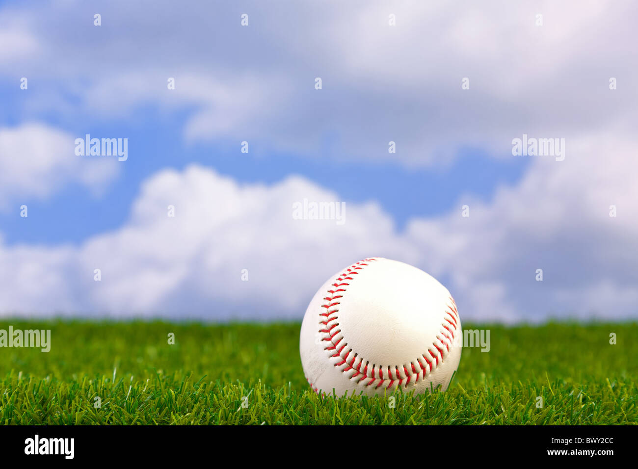 Photo of a baseball on grass with sky background. Stock Photo
