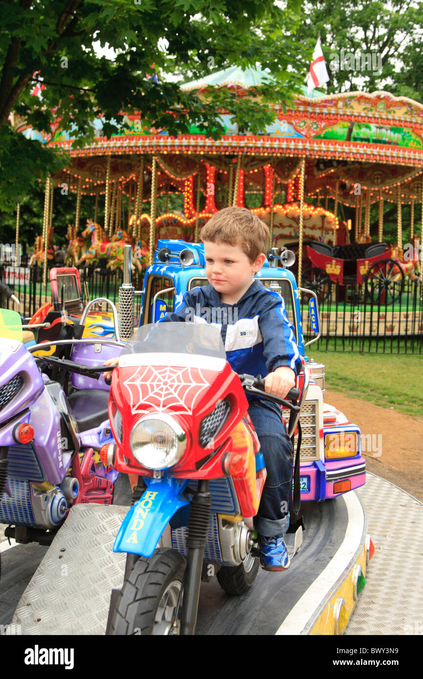 Boy on motorbike on merrygoround with traditional carousel in the