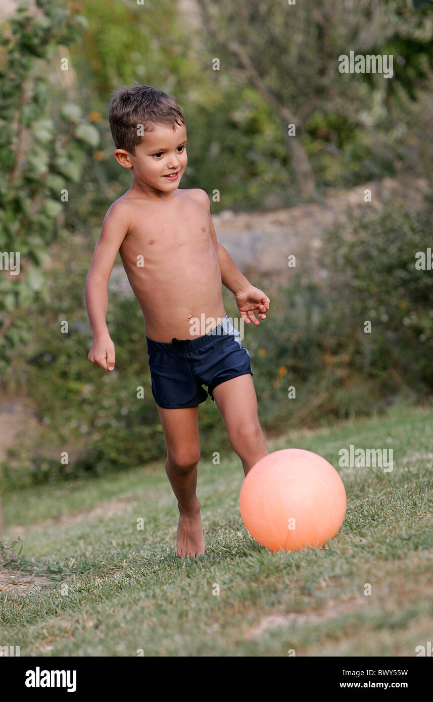 A young boy plays soccer bare foot in his garden Stock Photo