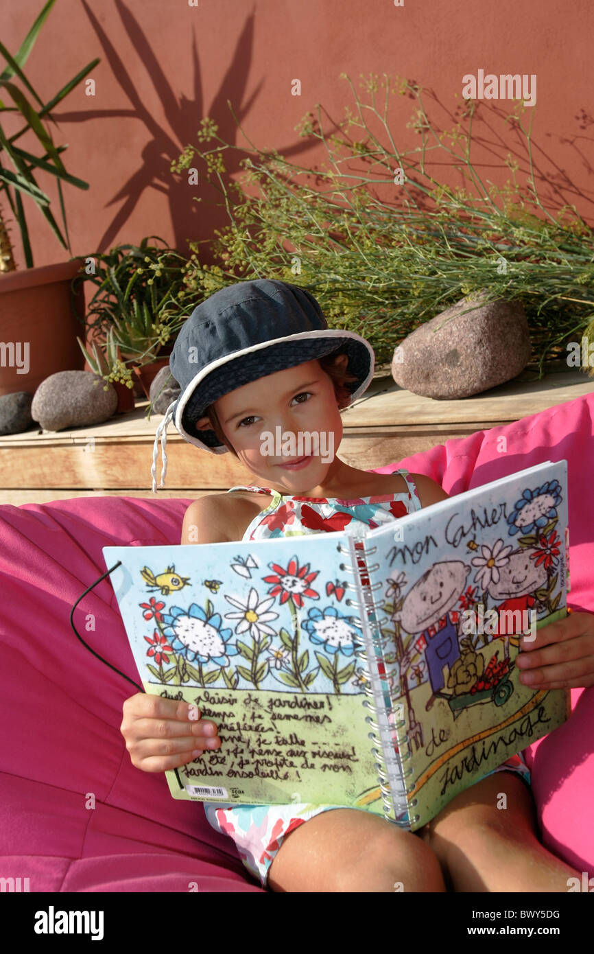 A young girl reading a book , relaxing near by his pool Stock Photo