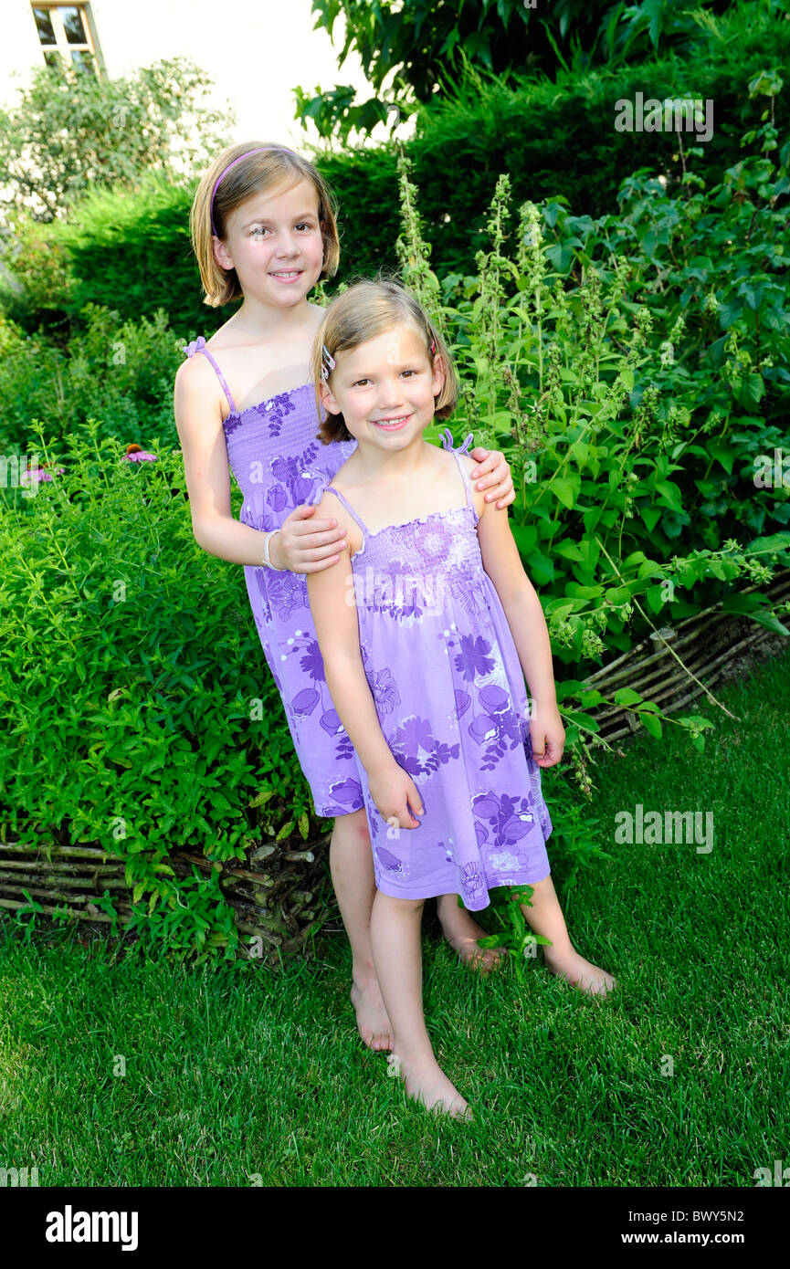 Two young girls posing in a garden in summertime Stock Photo
