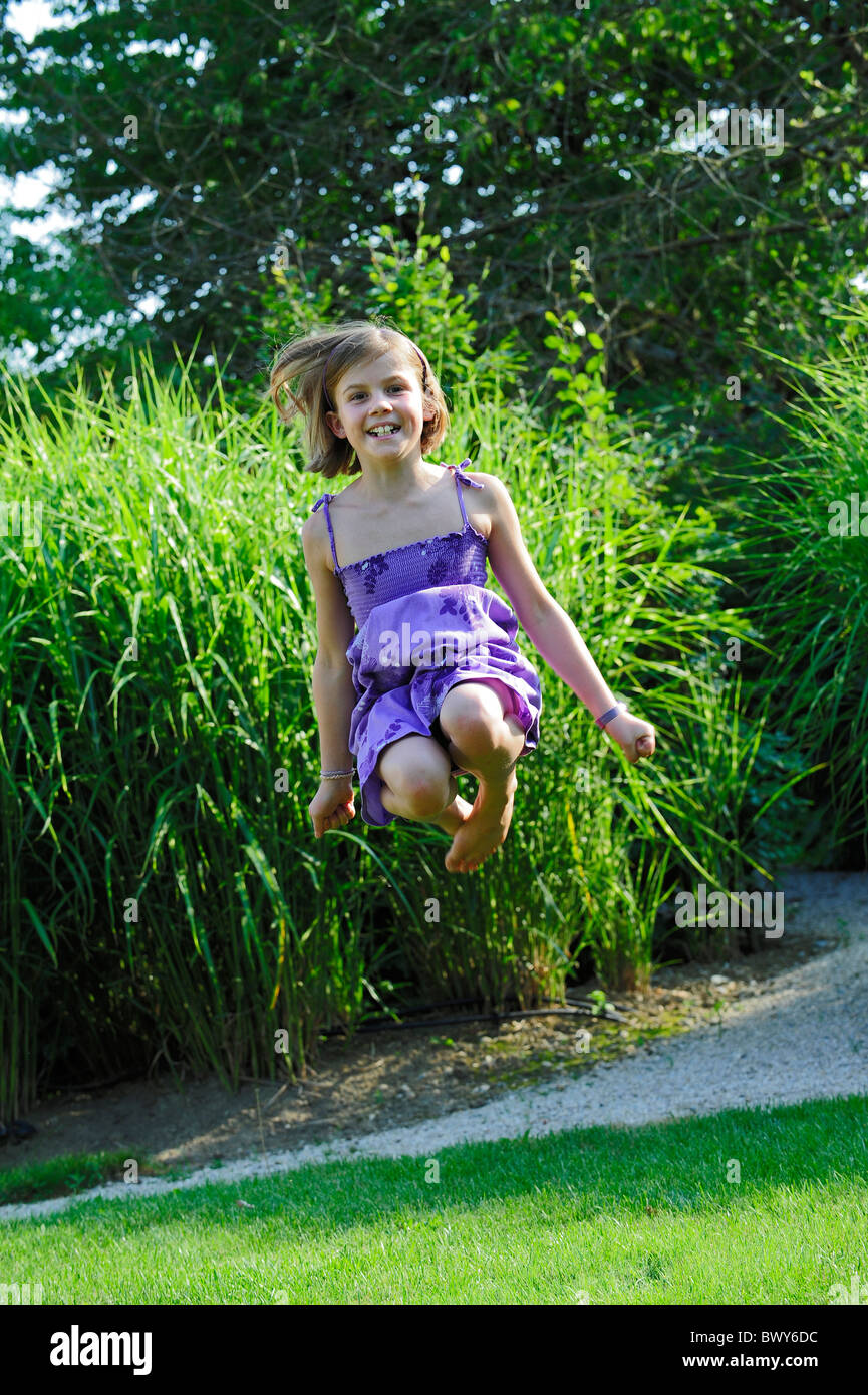 A young girl makes a jump in a garden, barre foot. Stock Photo