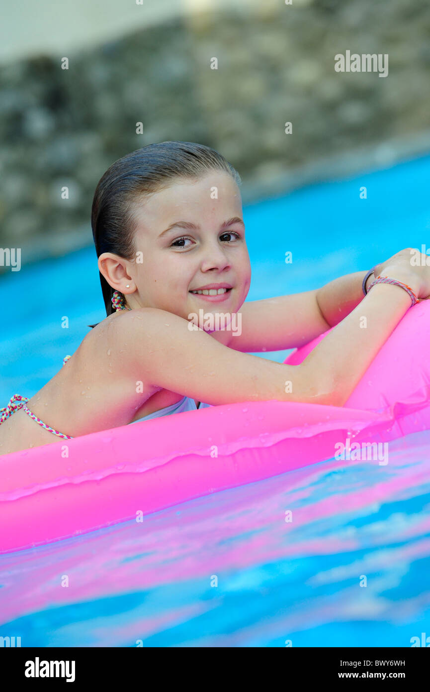 A young girl on a inflated bed at the swimming pool Stock Photo