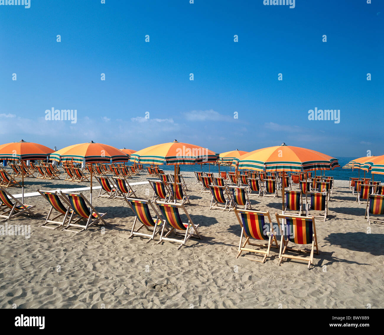 Italy Europe empty deck chairs orange rows sunshades beach seashore sea beach holidays Tuscany Stock Photo