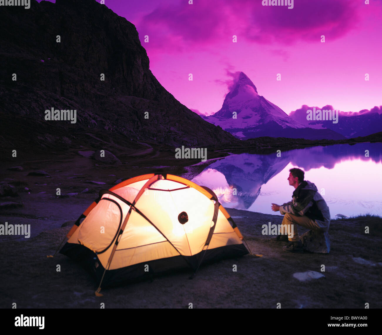 camping illuminates spectral filter man Matterhorn landmark mountain Switzerland Europe at night lake sea Stock Photo