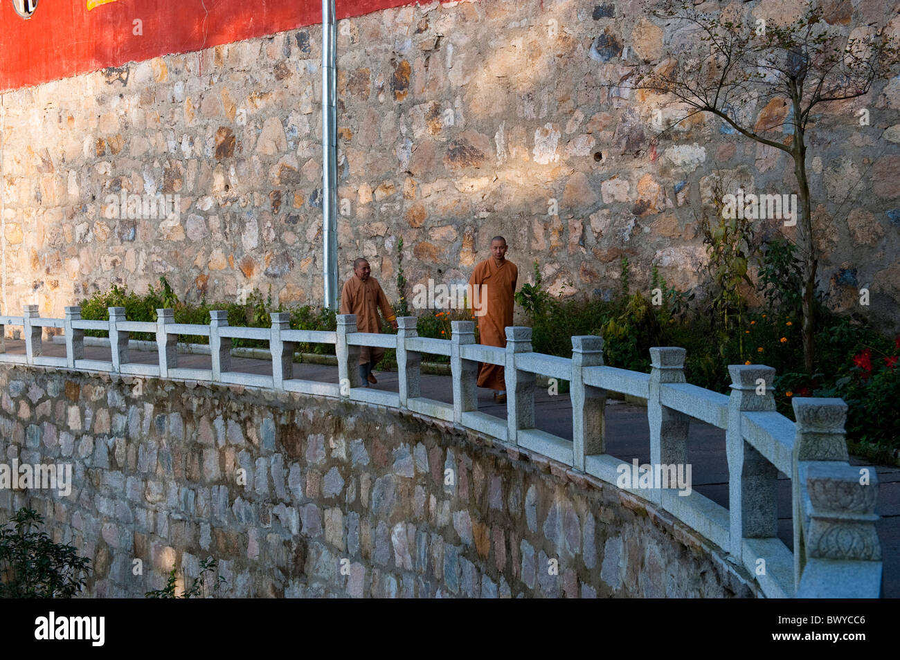 Chinese monks walking by tall temple wall, Tiantai Platform, Mount Jiuhua, Qingyang, Anhui Province, China Stock Photo