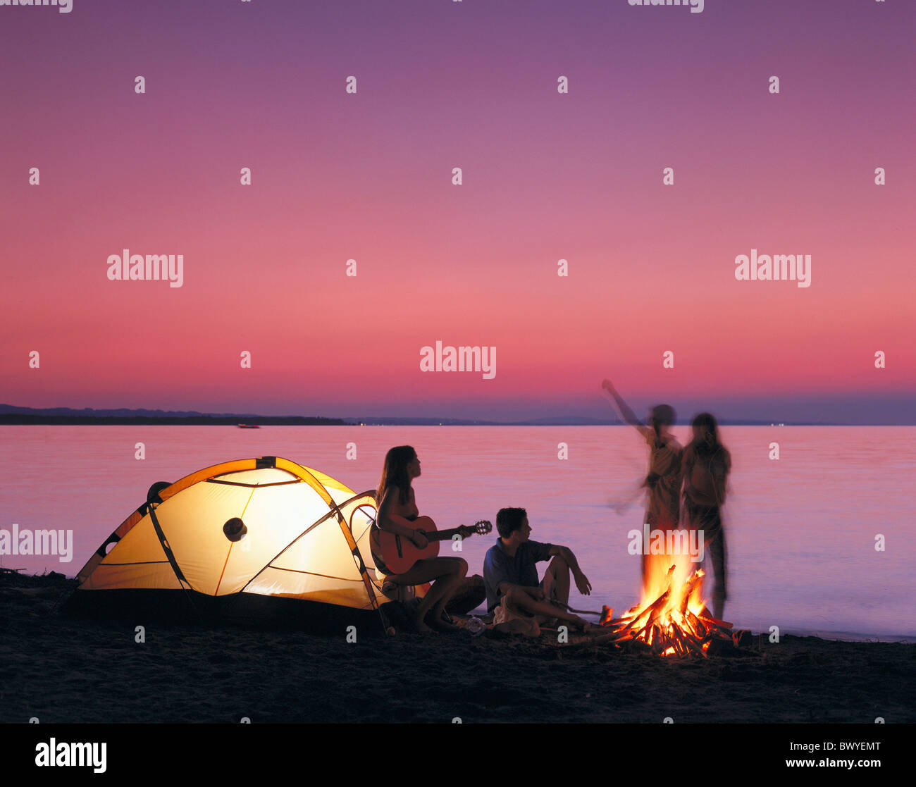 youngsters tents camping campinging camp warehouse food guitar campfire at night lake sea lake shore da Stock Photo