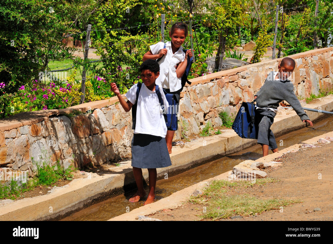 Three school children plays in the water duct. Prince Albert, South Africa. Stock Photo