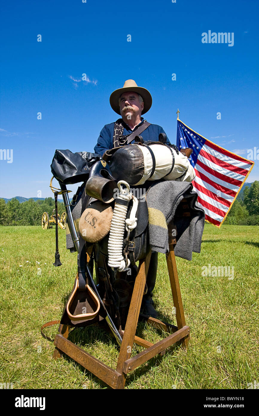 Man portrays sergeant from the 1880s, leaning on his horse saddle with