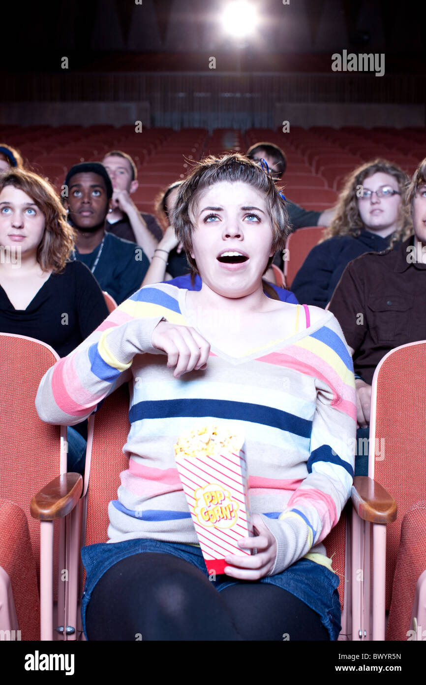Surprised Caucasian woman eating popcorn in movie theater Stock Photo