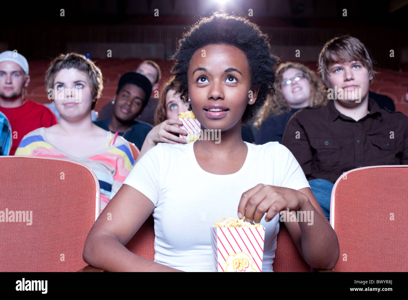 African woman eating popcorn in movie theater Stock Photo