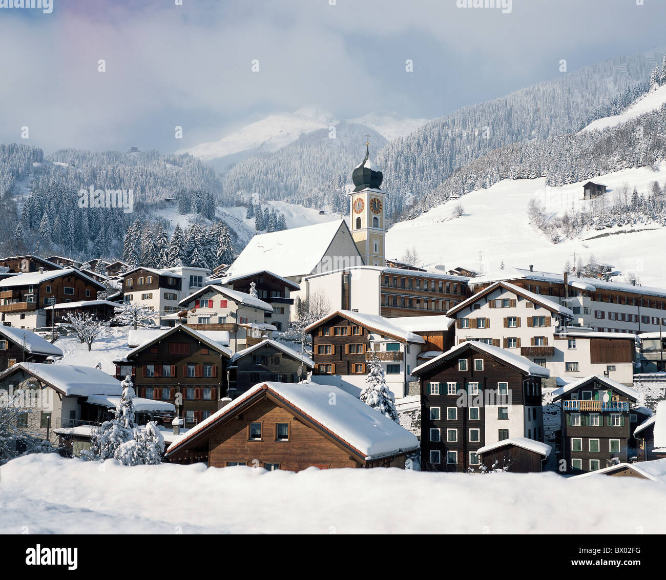 alpine Alps view mountains Disentis houses homes canton Graubunden Grisons Switzerland Europe church sno Stock Photo