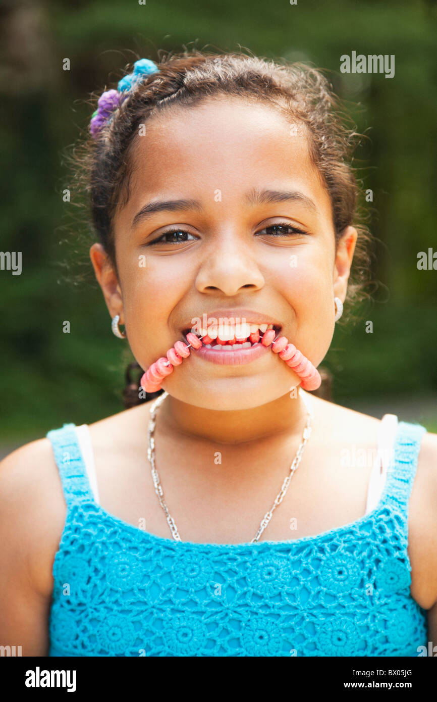 Close up of Hispanic girl biting candy necklace Stock Photo