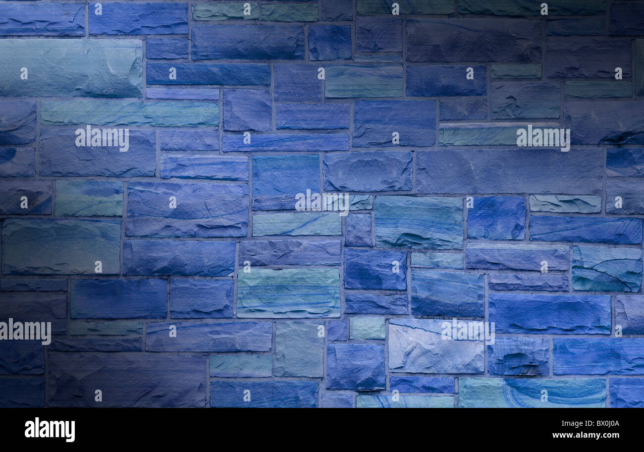 Blue masonry wall with irregular size rectangular stones dramatically lit diagonally Stock Photo