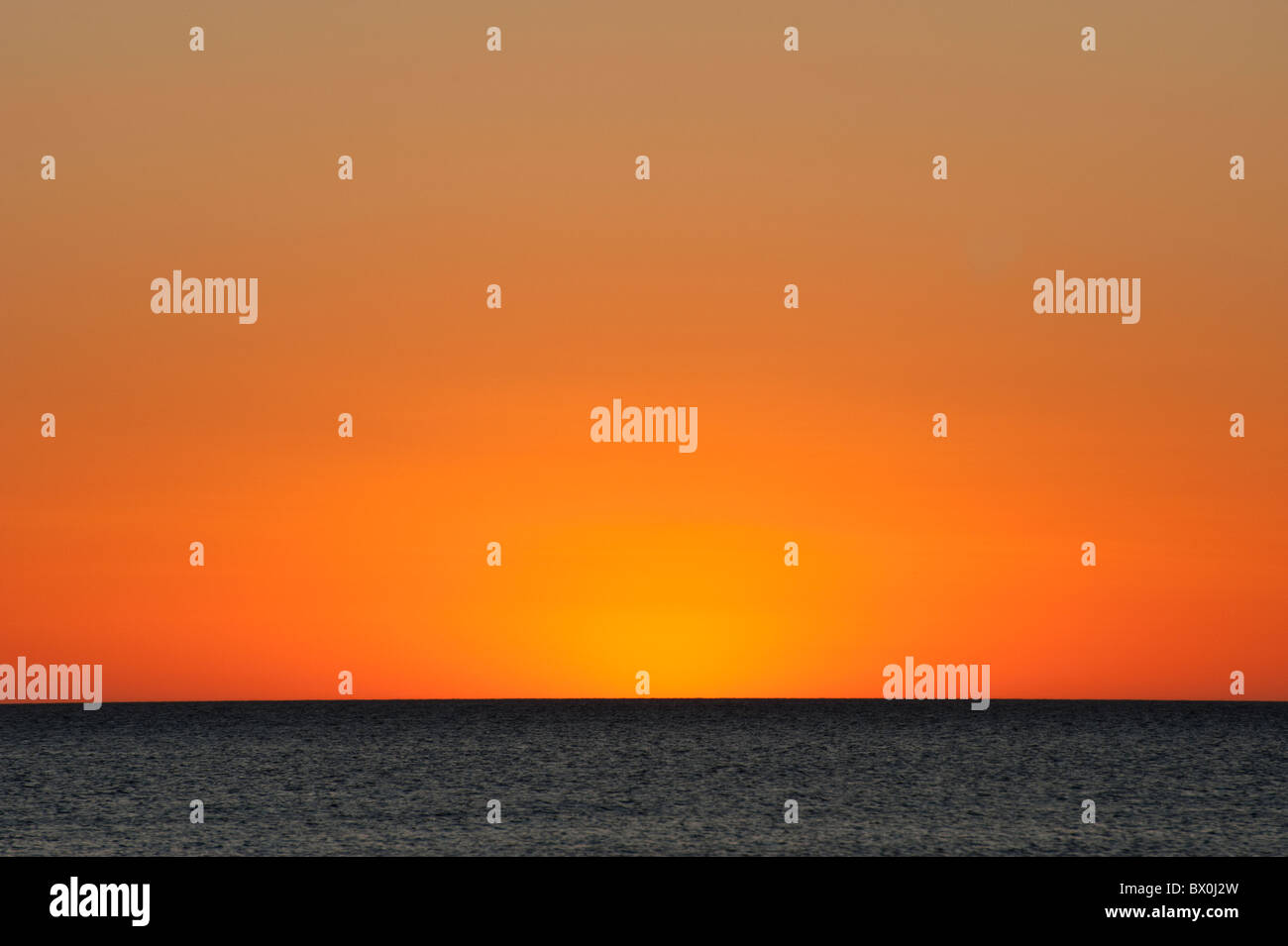 An orange sunset over the blue ocean Stock Photo - Alamy