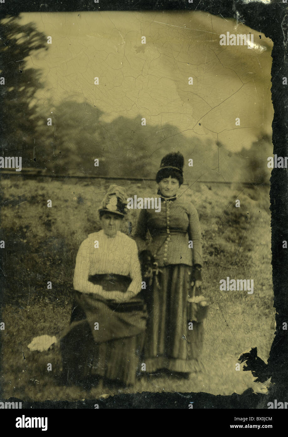 two women photographed outside in nature fashion 1870s 1880s 1890s black and white tin type photograph vertical Stock Photo