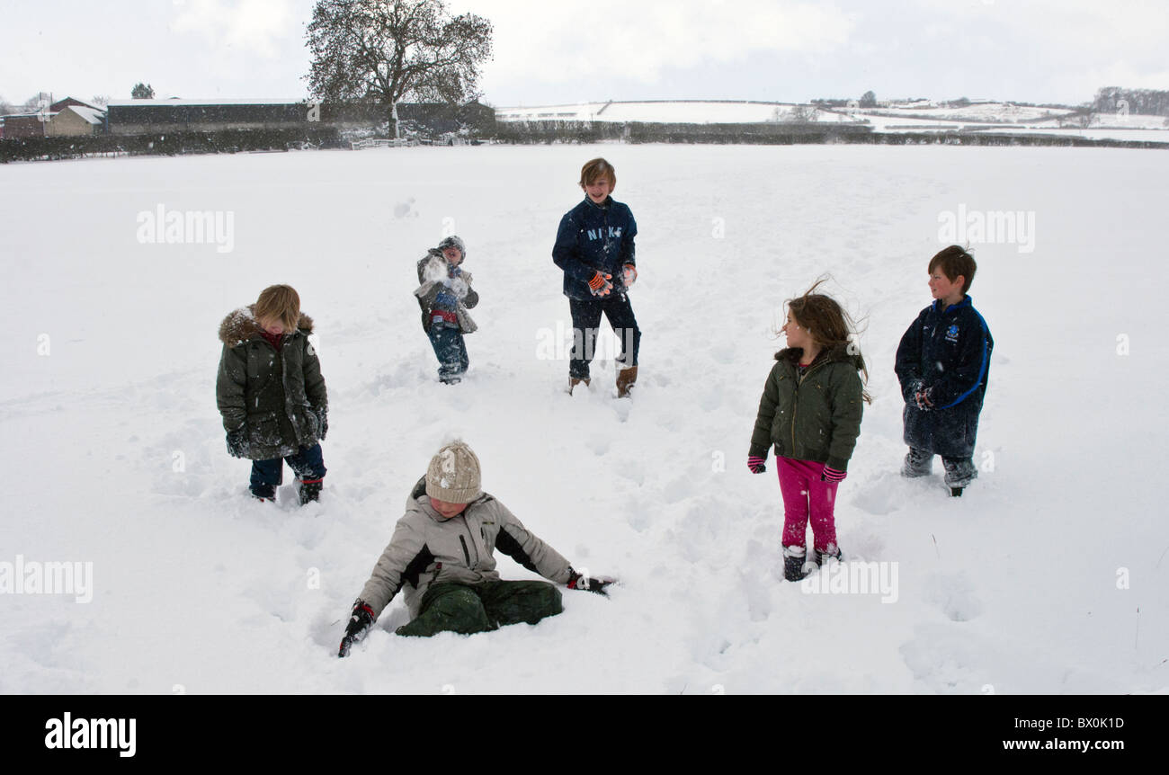 Children enjoying a snowball fight in a snow covered field in the UK Stock Photo