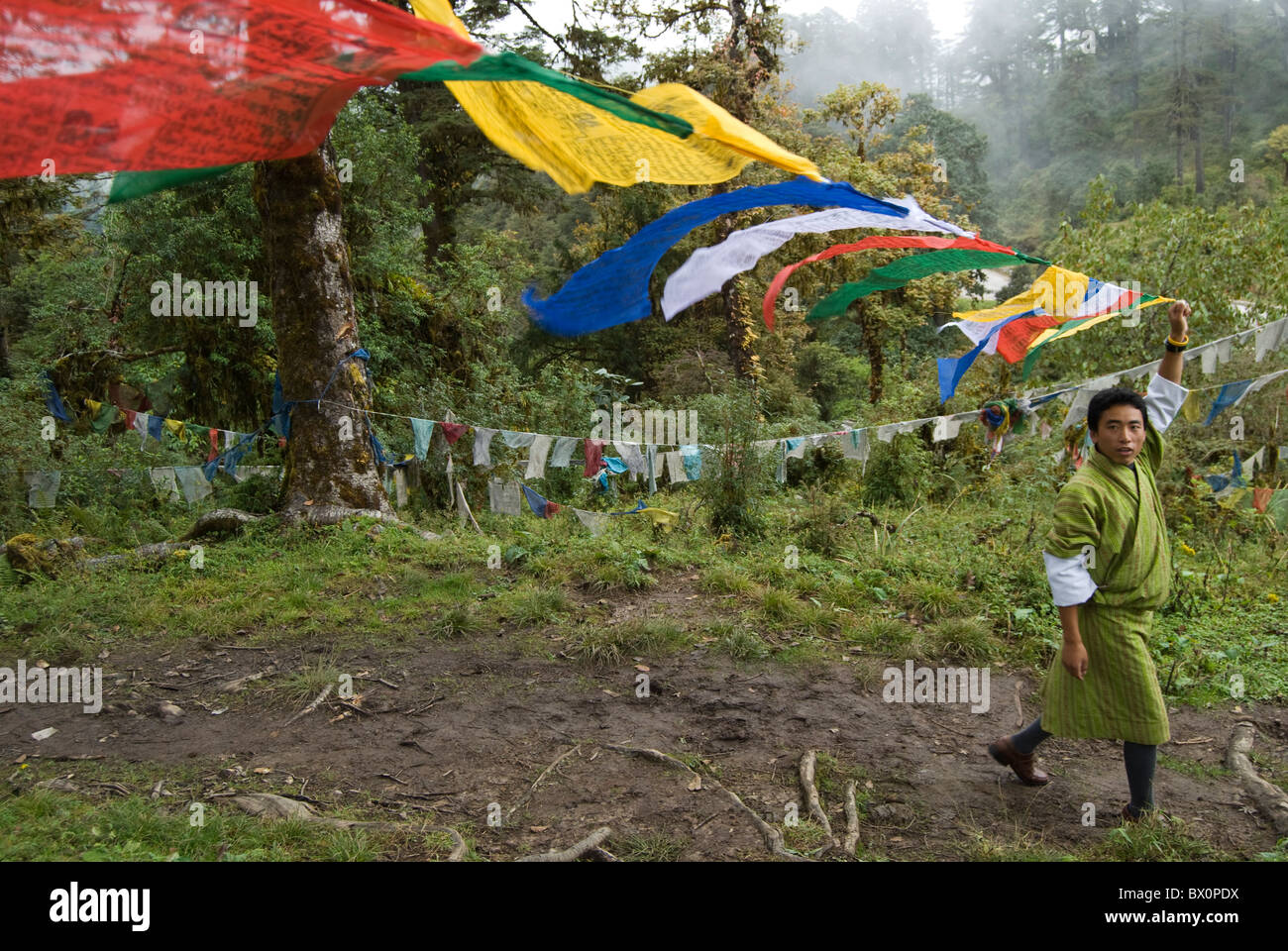 A Bhutanes man trying to find a place to hang/tie the prayer flags on the mountain of Dochula Pass, Bhutan. Stock Photo