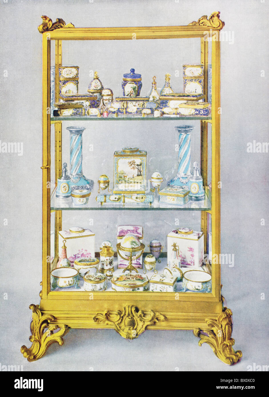 A glass case containing eighteenth century objects of art decorated in enamel. From The Queen The Lady's Newspaper, 1935. Stock Photo