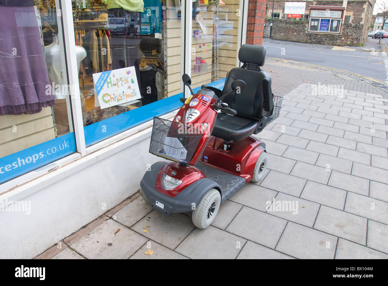 Electric mobility scooter outside of charity shop, England, UK Stock Photo
