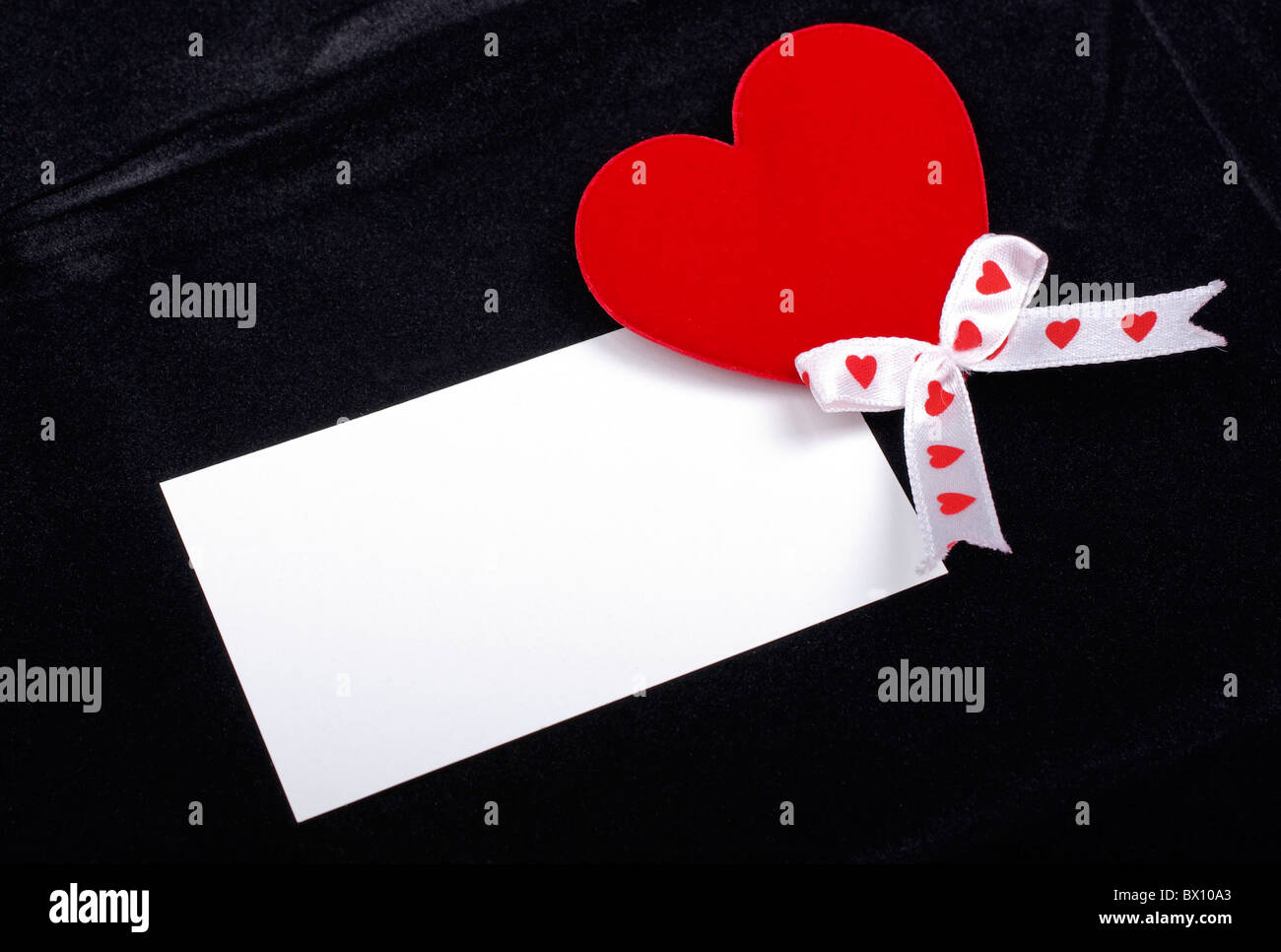 Red heart and white card macro isolated on black velvet background ...