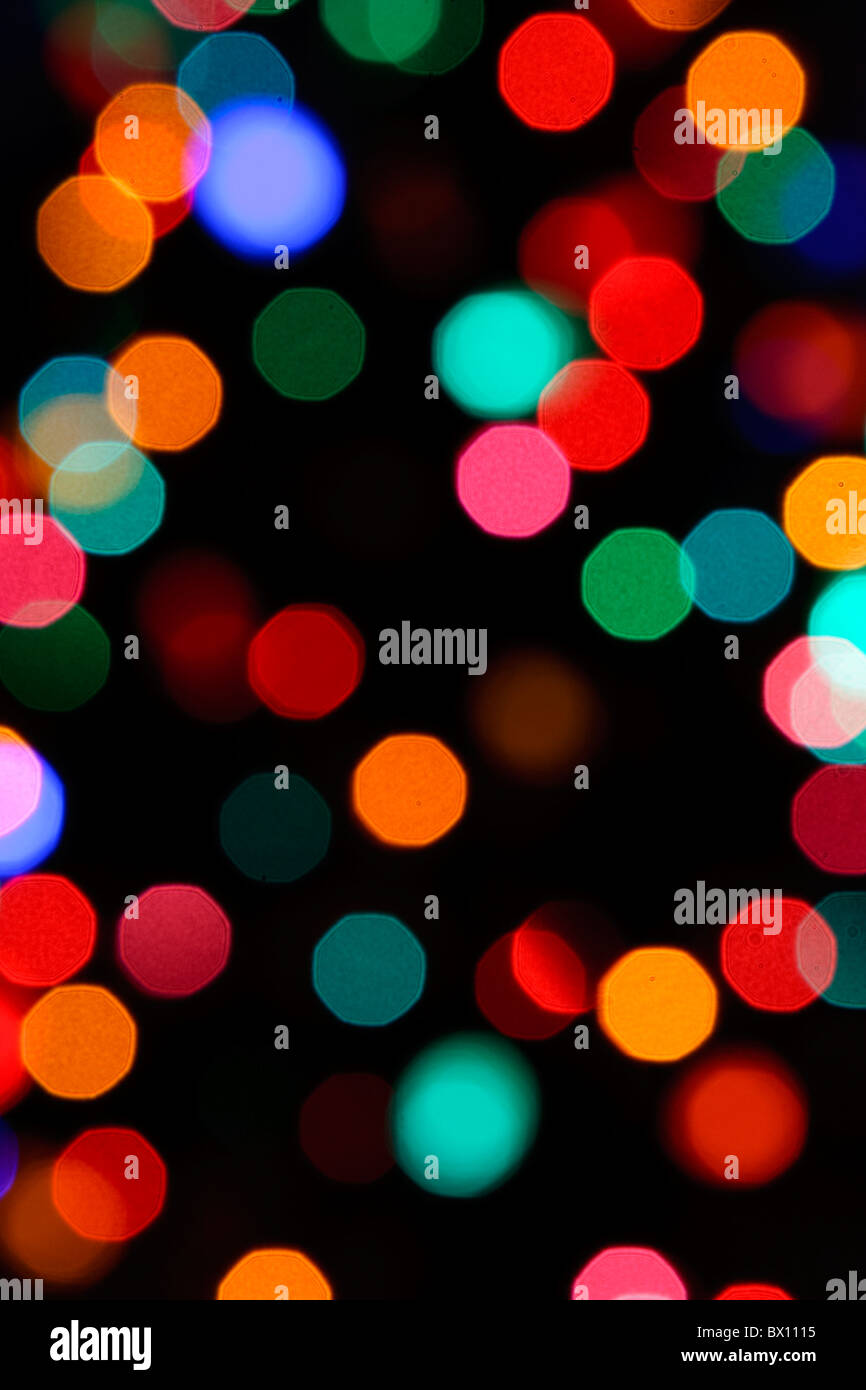 Slightly octagon bokeh circles of out of focus Christmas lights in a dark room. Stock Photo