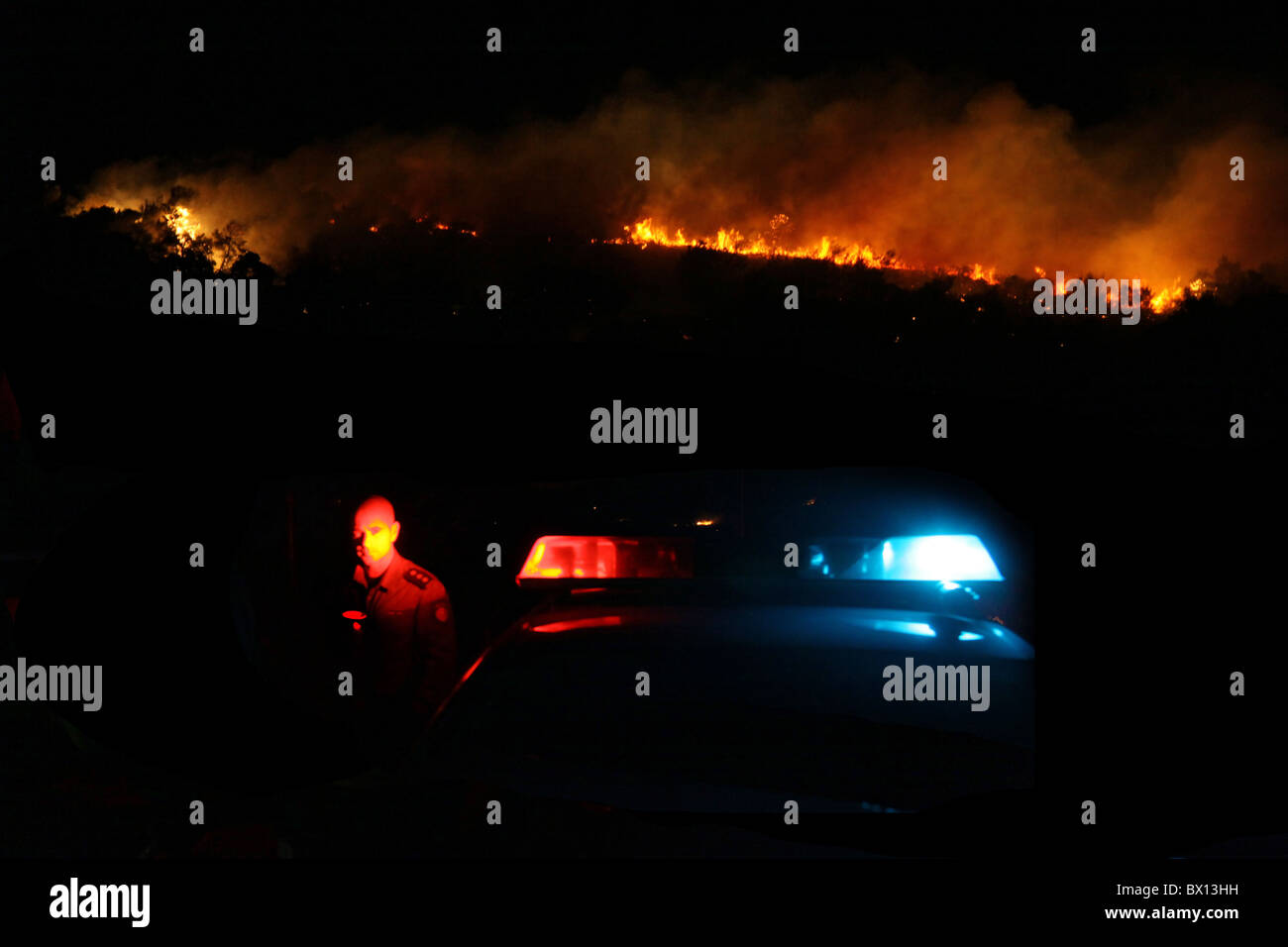 A policeman stands near massive forest fire on Mount Carmel in northern Israel. The fire consumed much of the Mediterranean forest covering the region and claimed 44 lives, making it the deadliest in Israeli history. Stock Photo