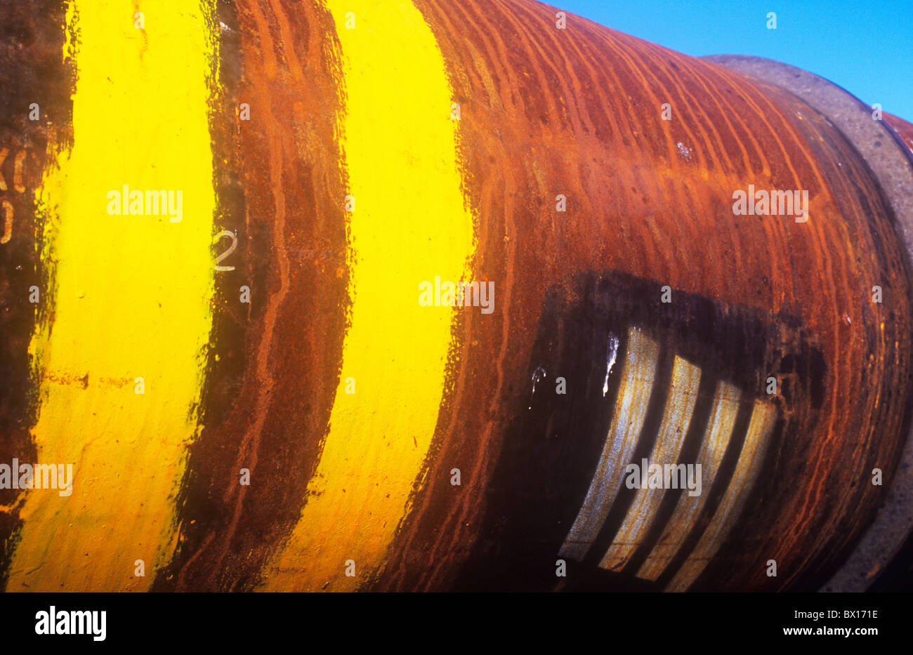 Large metal tube with lightly rusted surface and yellow and silver ID stripes painted and