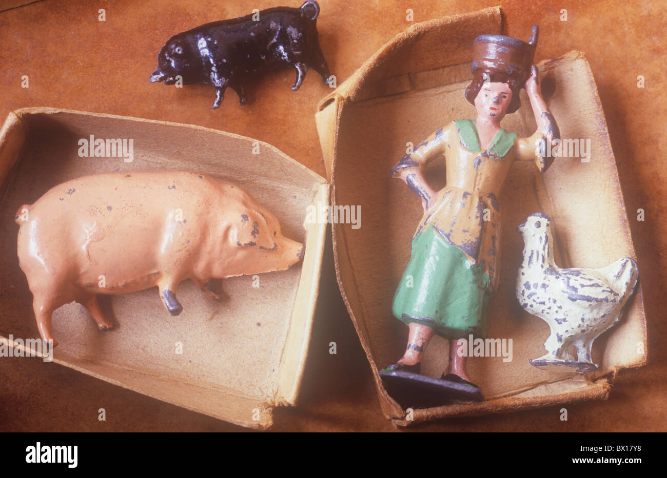 Close up of two small card trays with scratched metal lead models of woman with milk bucket on head plus pigs and chicken Stock Photo